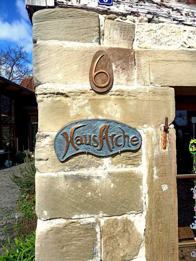 Eingang Haus Arche – Hausschild am historischen Sandsteinpfeiler
